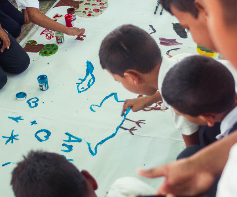 Kids finger paint on a large piece of paper
