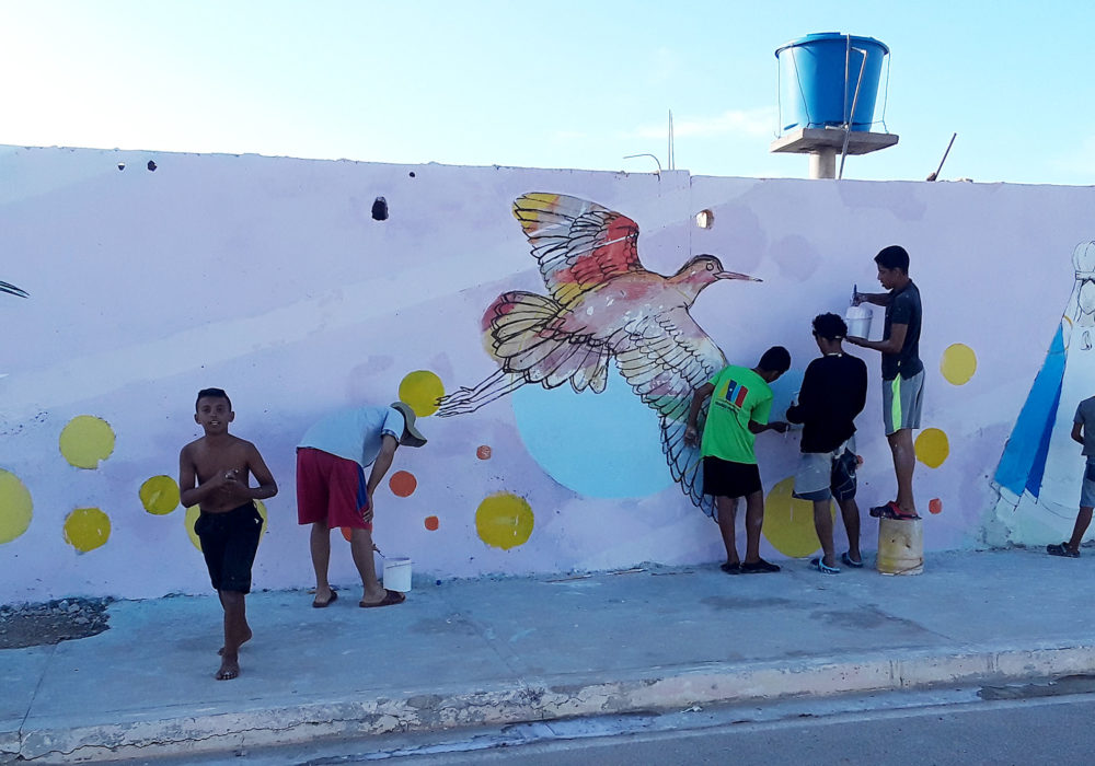 Children painting mural with birds in Isla de Coche