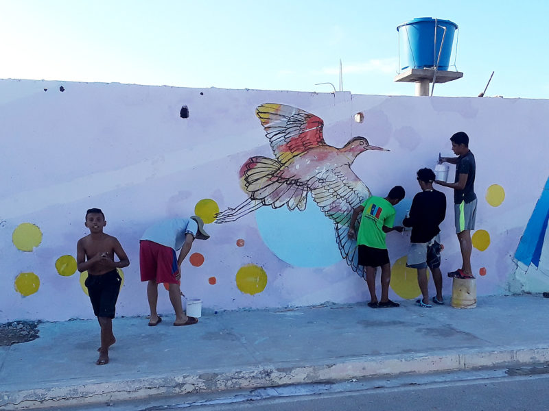Children painting mural with birds in Isla de Coche